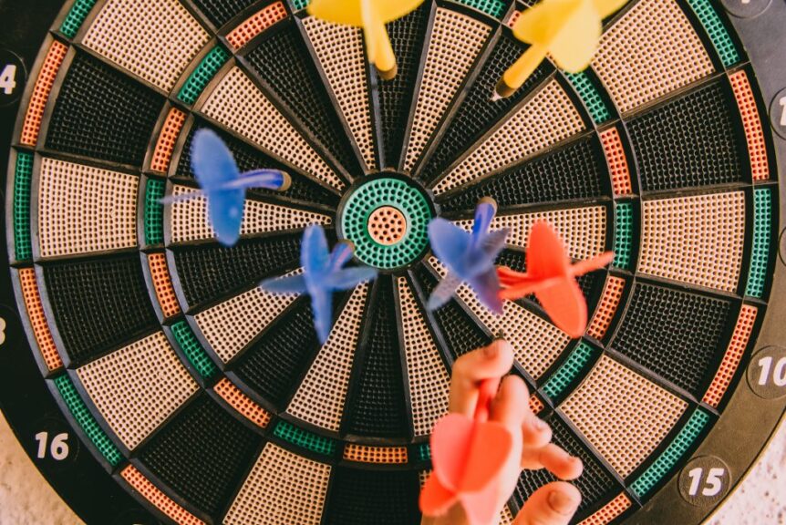 Colorful darts hitting a dartboard, symbolizing the randomness of stock market picks compared to the secure financial strategies offered by SureWealth.