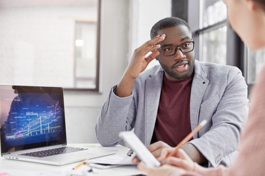 A Sure Wealth Strategist with glasses engaging in a discussion about smarter retirement alternatives. A laptop displaying financial charts sits nearby, symbolizing data-driven retirement planning strategies.